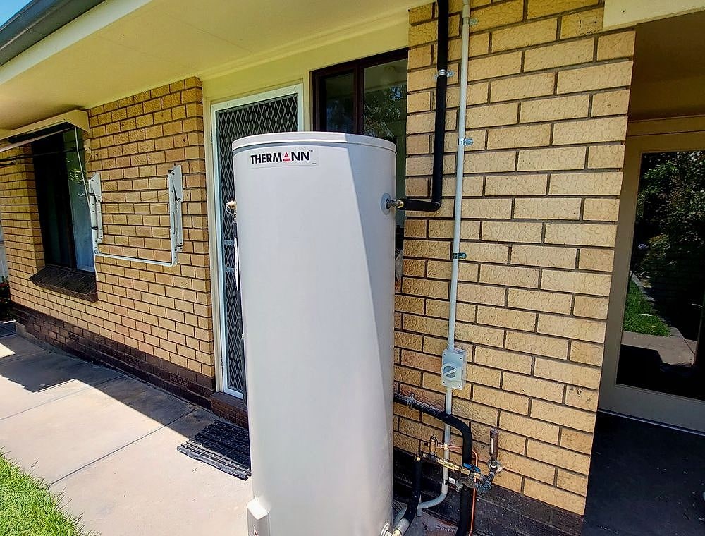 Electric storage hot water system installed beside a home